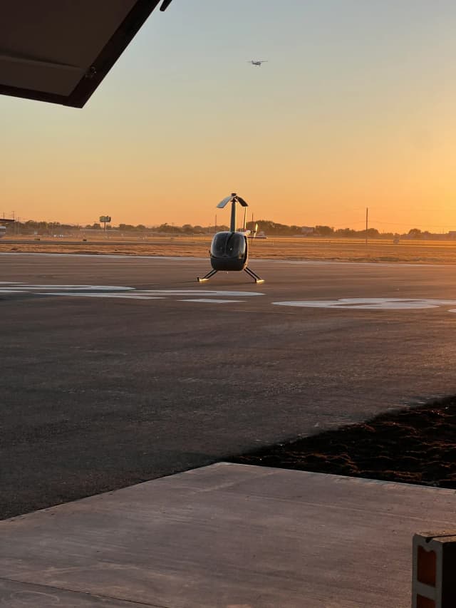 Helicopter on the apron at golden hour, framed by the open hangar door